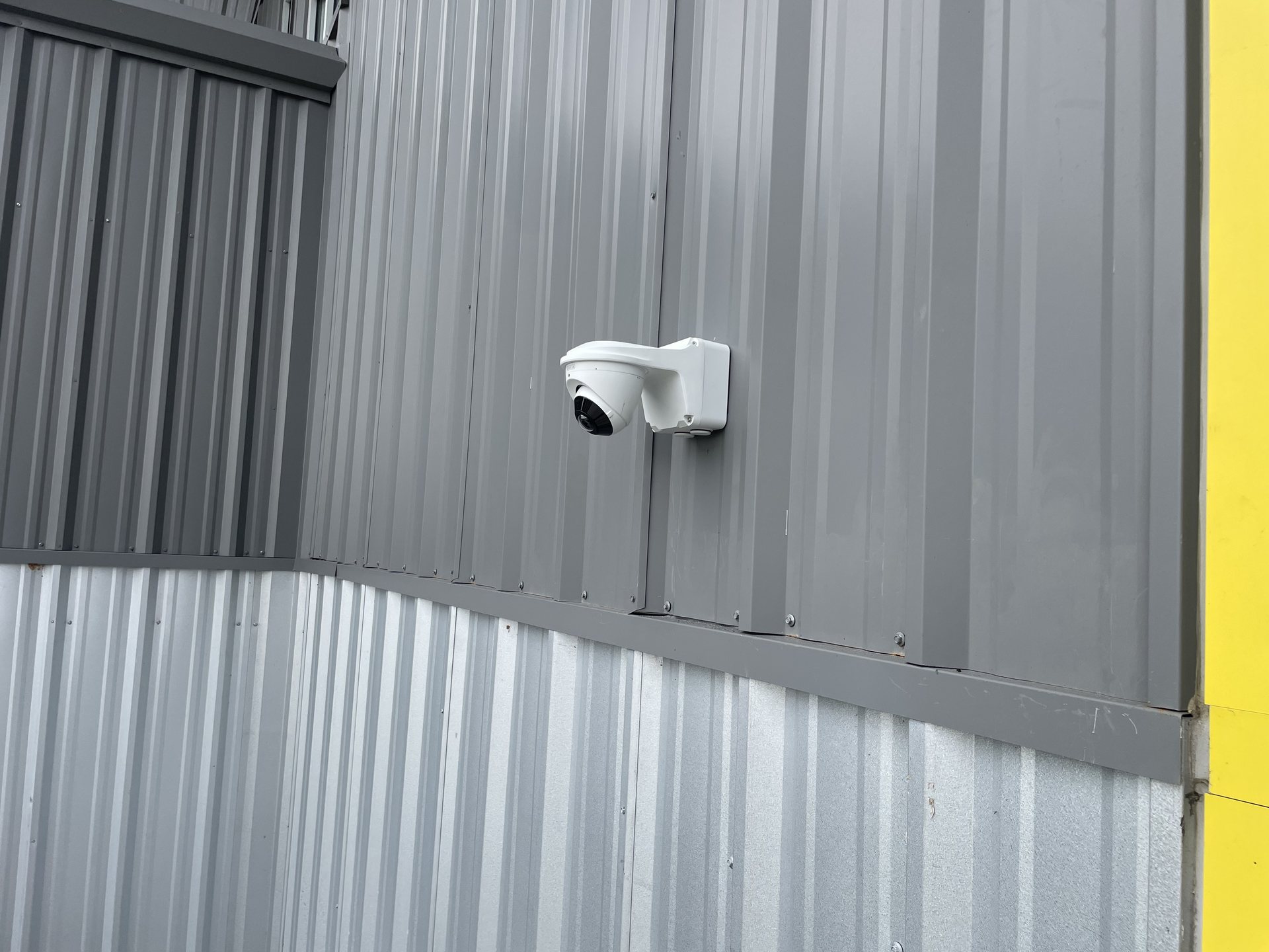 White dome security camera mounted on the gray metal exterior wall of a Winter Haven commercial building