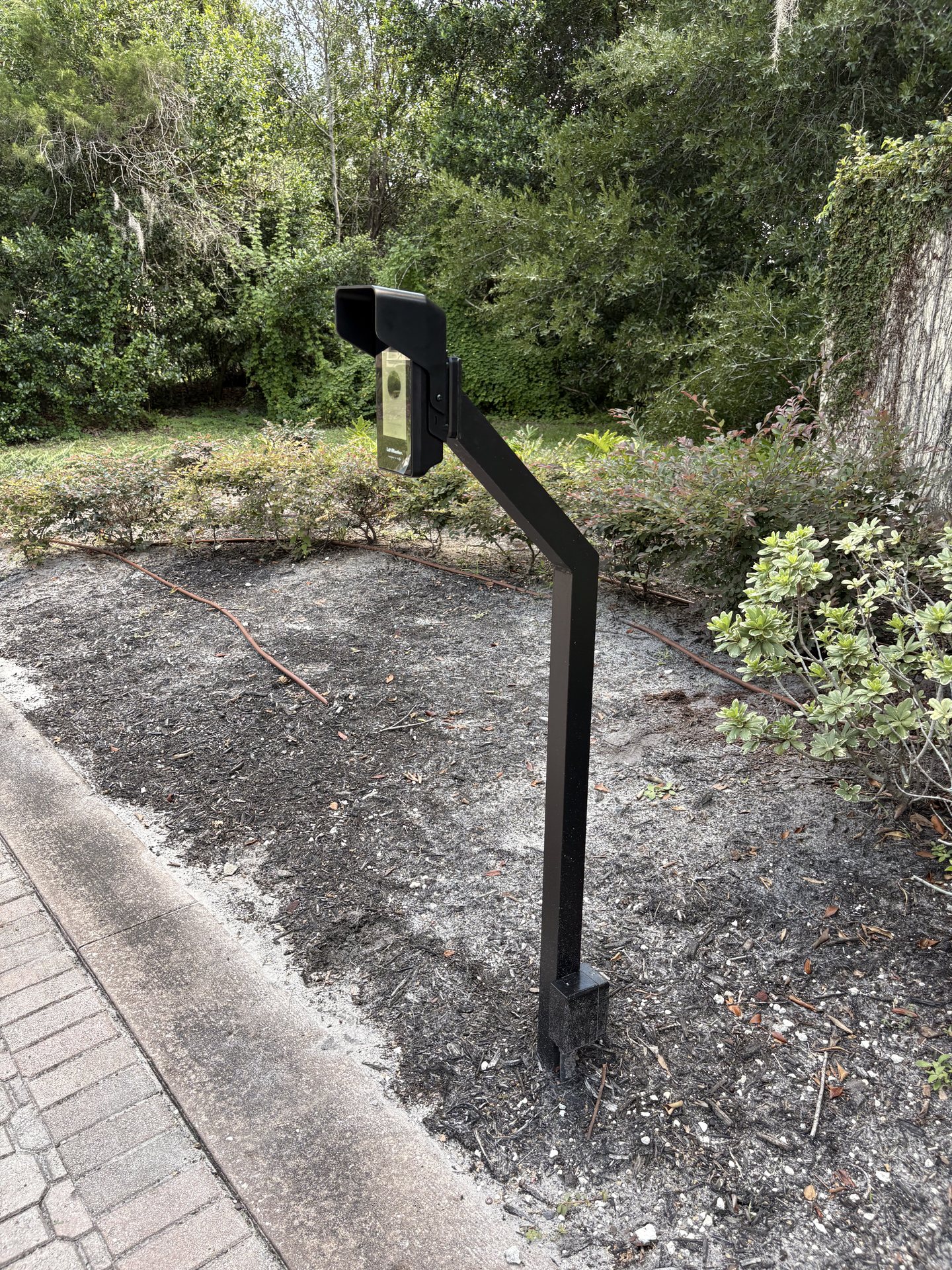 Intercom pedestal base set in landscaping with protected cable run to the gate operator
