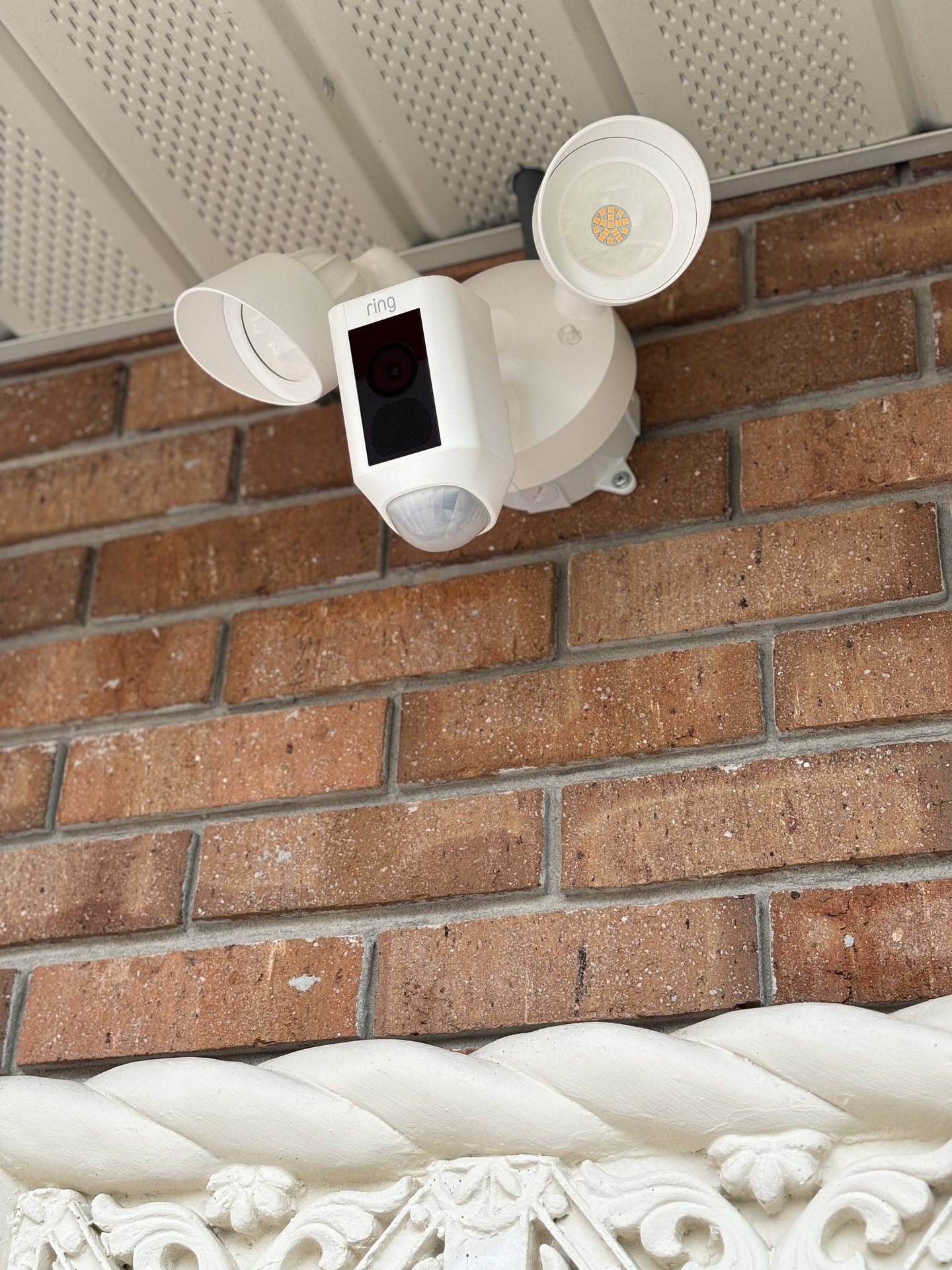 Close-up of a floodlight camera mounted to brick with concealed power routing