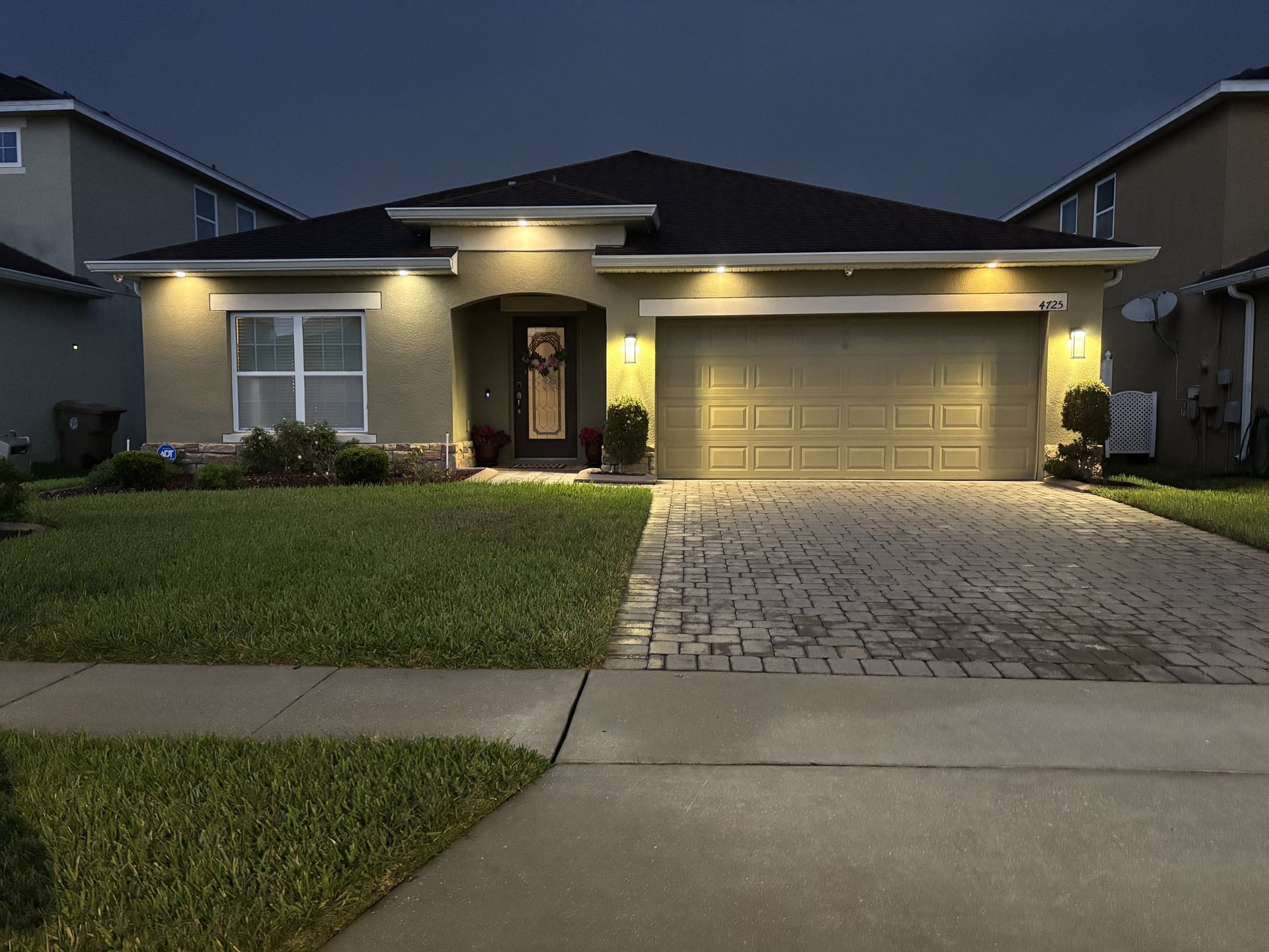 Evening exterior of the home showing smart-controlled landscape and garage lighting