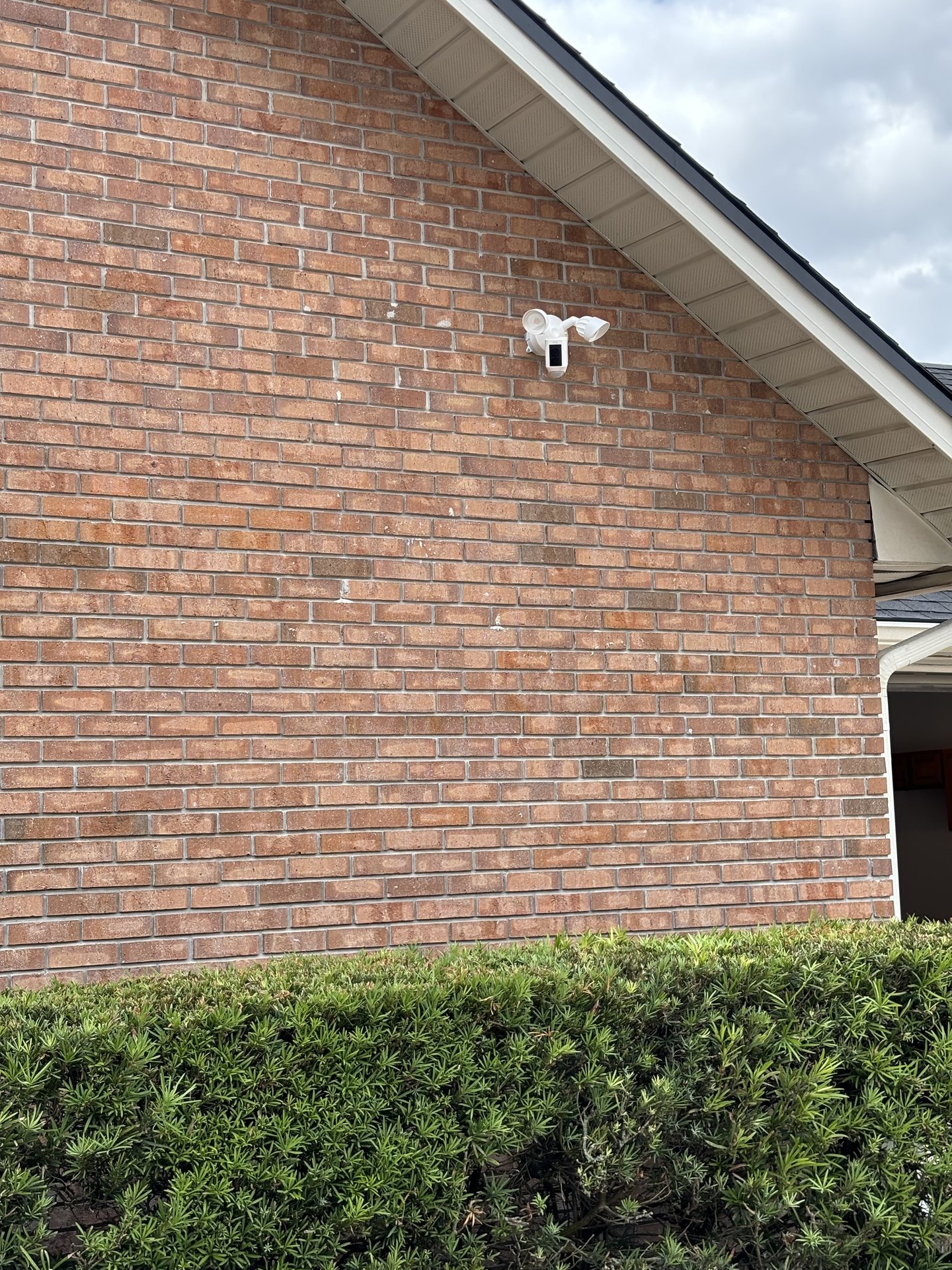 Security camera mounted high on the brick exterior with a clear view of the side yard