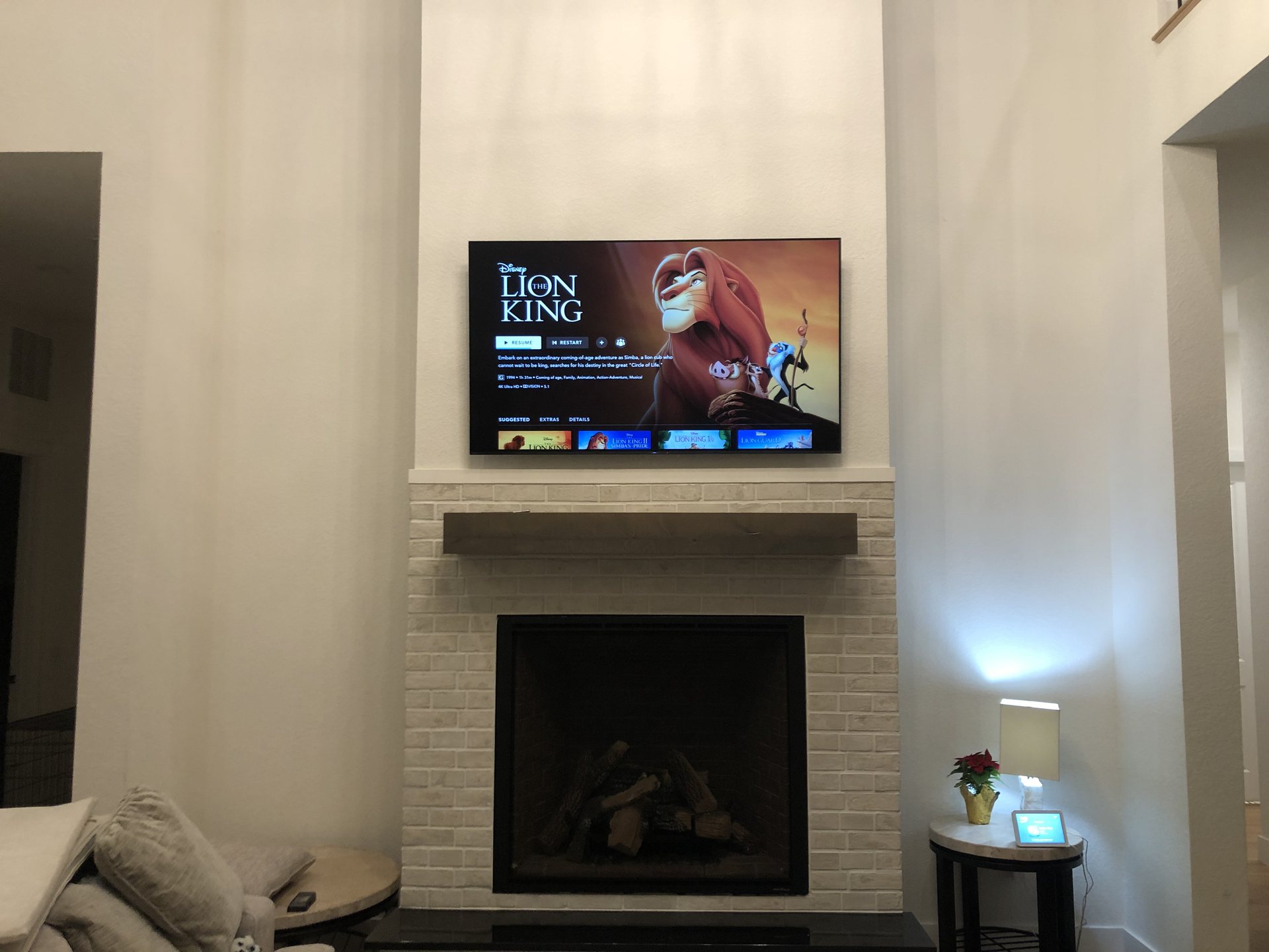 Wide view of the two-story living room with the above-fireplace TV installation and accent lighting