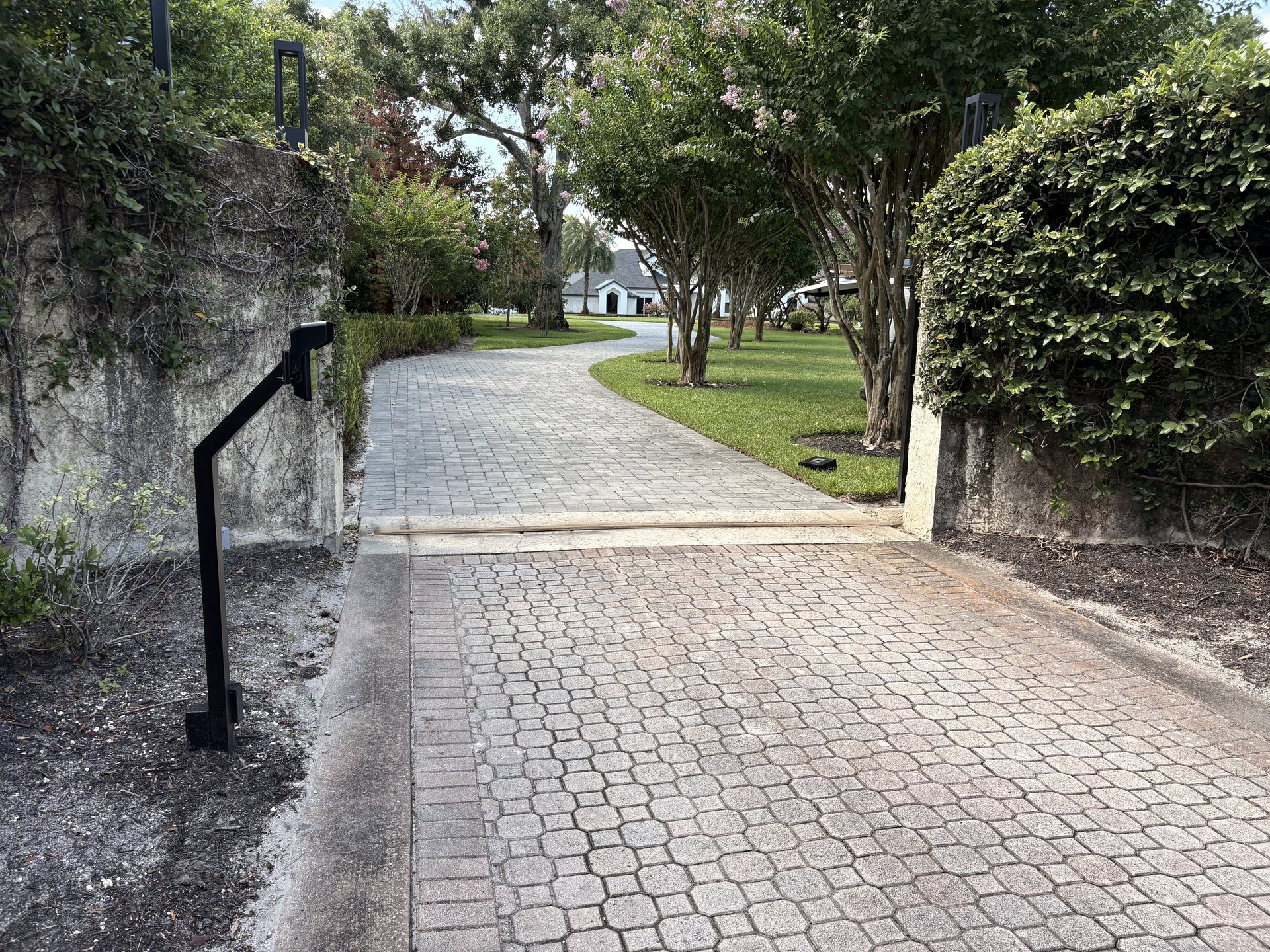 Paver driveway approach showing the intercom pedestal position relative to the automated gate