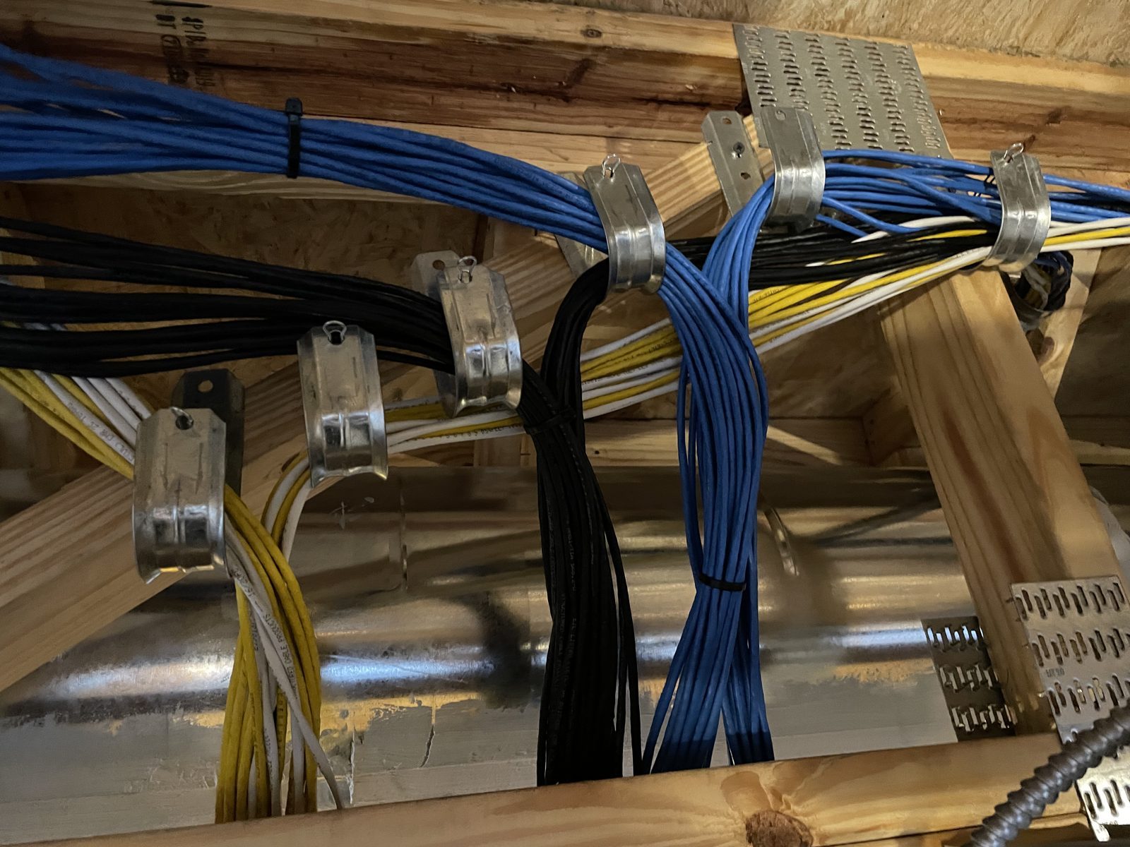 Organized low-voltage cable bundles routed along supported overhead pathways at a commercial job site