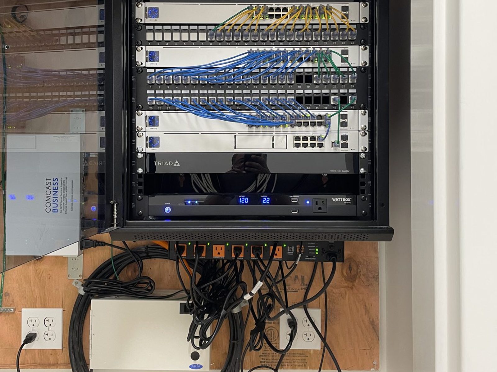 Wall-mounted commercial network rack with patch panels and switches installed at an Orlando business